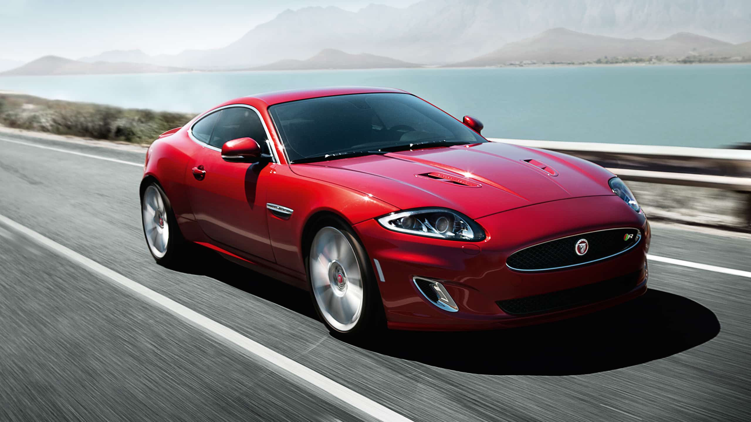 Jaguar XK running on bridge connected with Sea and mountains