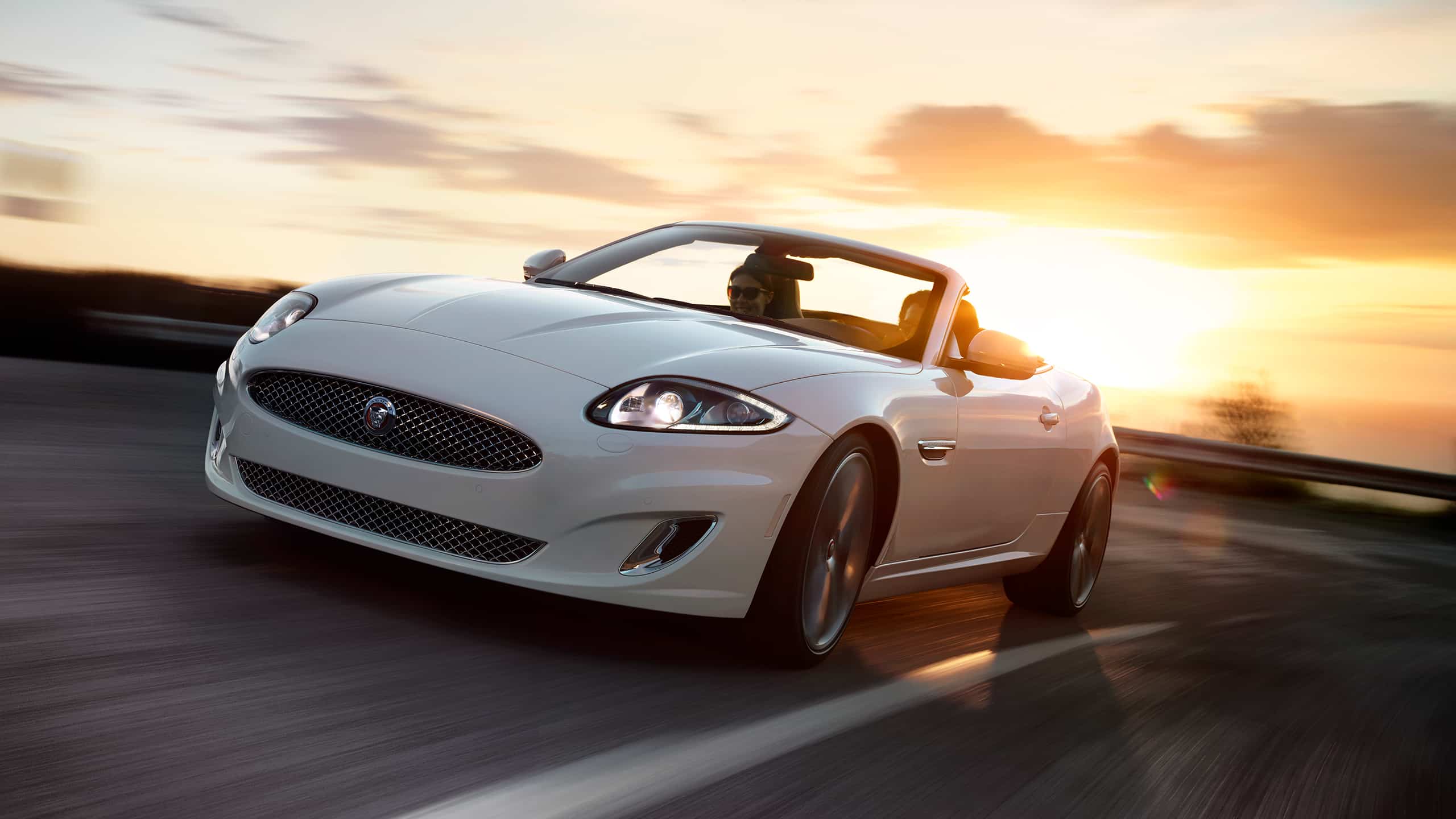 Jaguar XK running on the road and with sunset background 